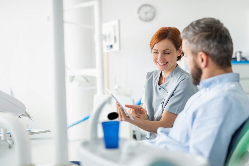 Female dental professional discussing treatment information with a seated patient inside a bright and modern dental clinic.