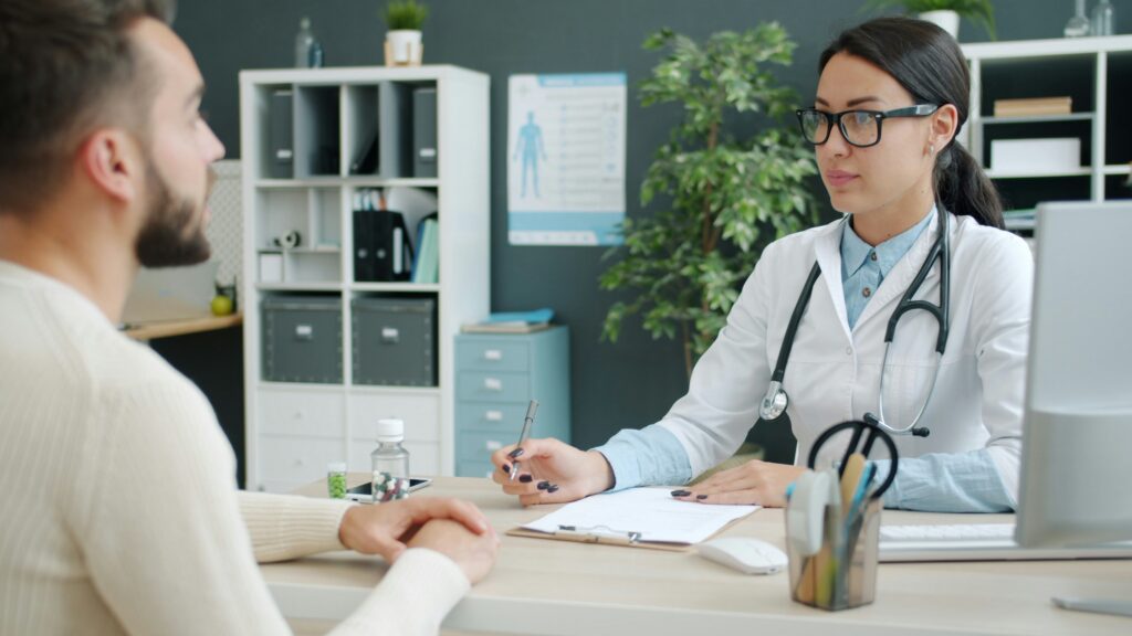 Doctor consulting with a patient in a medical office while taking notes during an appointment.